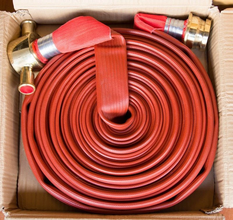 Red fire fighting hose reel with metal nozzle and connectors for emergency fire protection